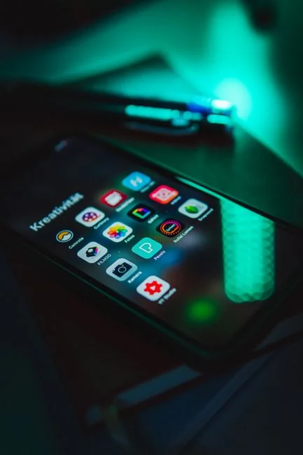 Woman using smartphone for online shopping with credit card in hand, festive background lighting.